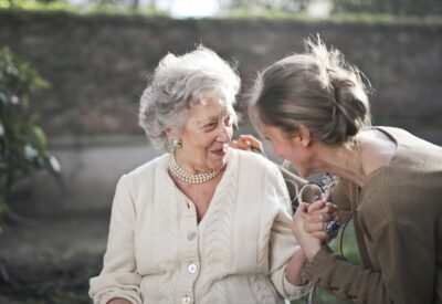 elderly woman smiling while caregiver provides support and companionship representing long term care planning before crisis